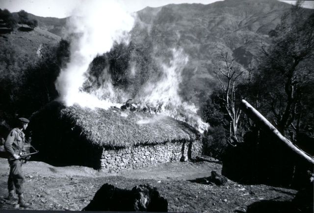 Soldat français devant une maison en feu pendant la Guerre d'Algérie