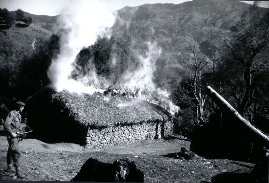 Soldat français devant une maison en feu pendant la Guerre d'Algérie