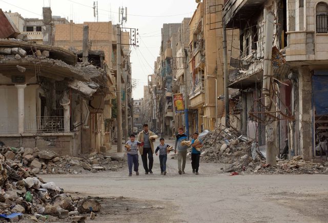 Une famille dans les rues dévastées de Deir al-Zor, Syrie