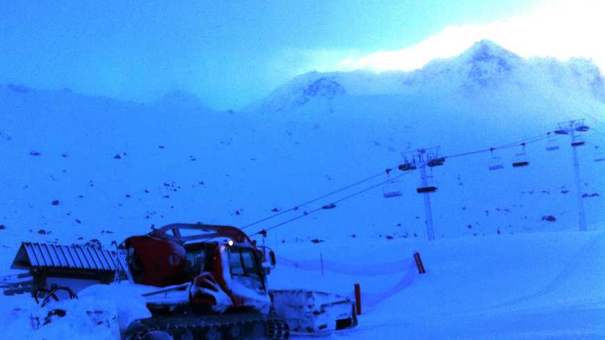Un saisonnier au volant d'une dameuse en action, au petit matin à Val Thorens (Savoie).