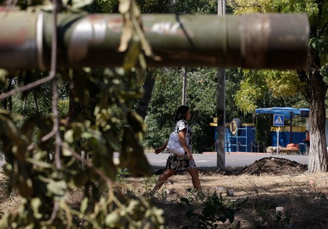 Une femme marche près d'un tank à Novoazovsk en Ukraine