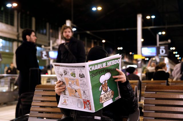 Un homme lit Charlie Hebdo a la Gare de Lyon