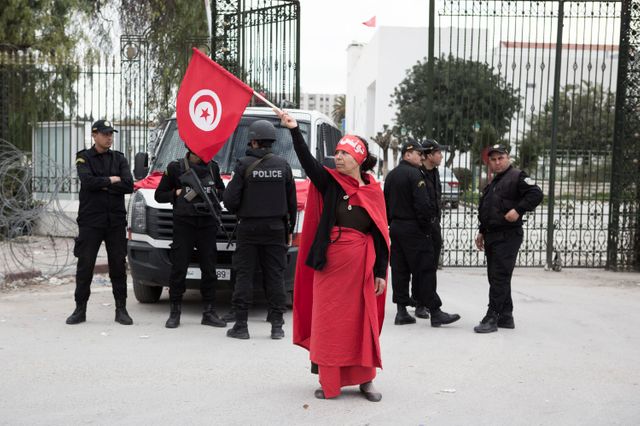 Une femme brandit le drapeau tunisien devant le musée du Bardo où 21 personnes ont été tuées lors de l'attentat, Tunis, 20/03/15