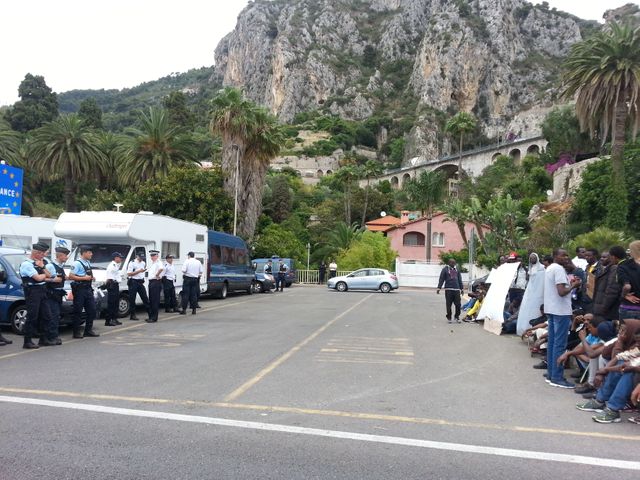 Une centaine de migrants face à des policiers français les empêchant de passer