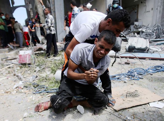 A Rafah un Palestinien pleure alors qu'on évacue le cadavre de sa mère des décombres de leur maison détruite par une frappe
