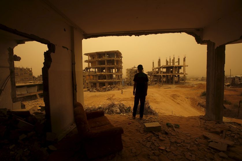 A Palestinian stands inside the remains of a house, during a sandstorm in Gaza.