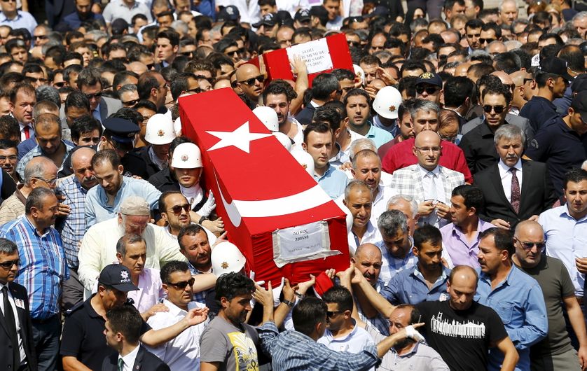People carry the flag-draped coffins of police officers Fehmi Sahin and Ali Koc, two of the 14 police officers who were killed d