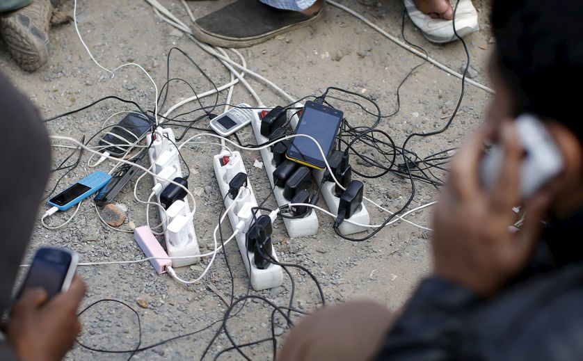 Des migrants rechargent leur portable à Calais