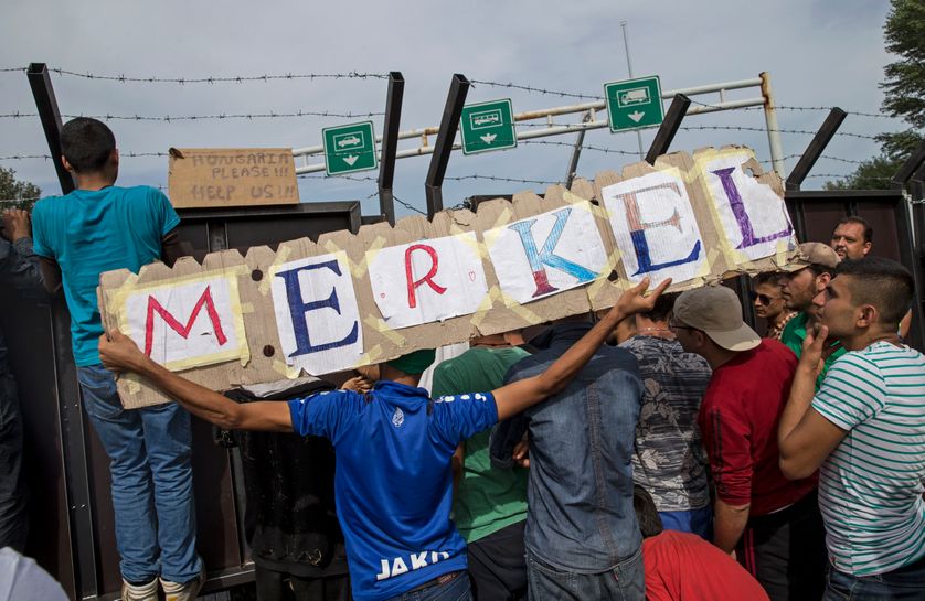 Migrants hold a banner reading "Merkel".