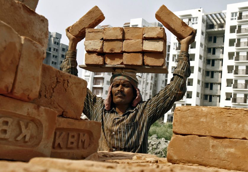 A labourer stacks bricks on his head at the construction site of a residential complex in Kolkata.