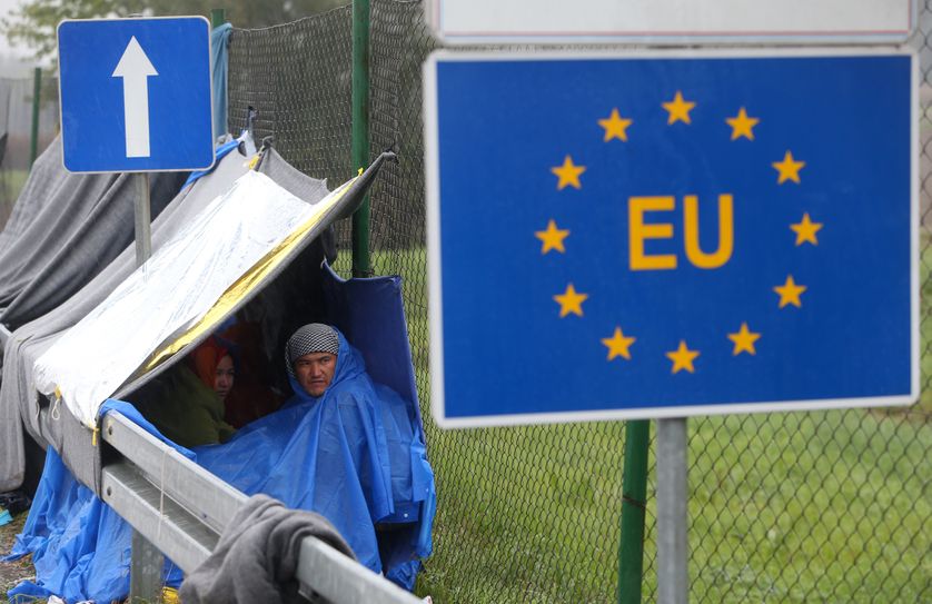 An EU sign is seen as migrants wait in the no man's land to cross the border to Slovenia.