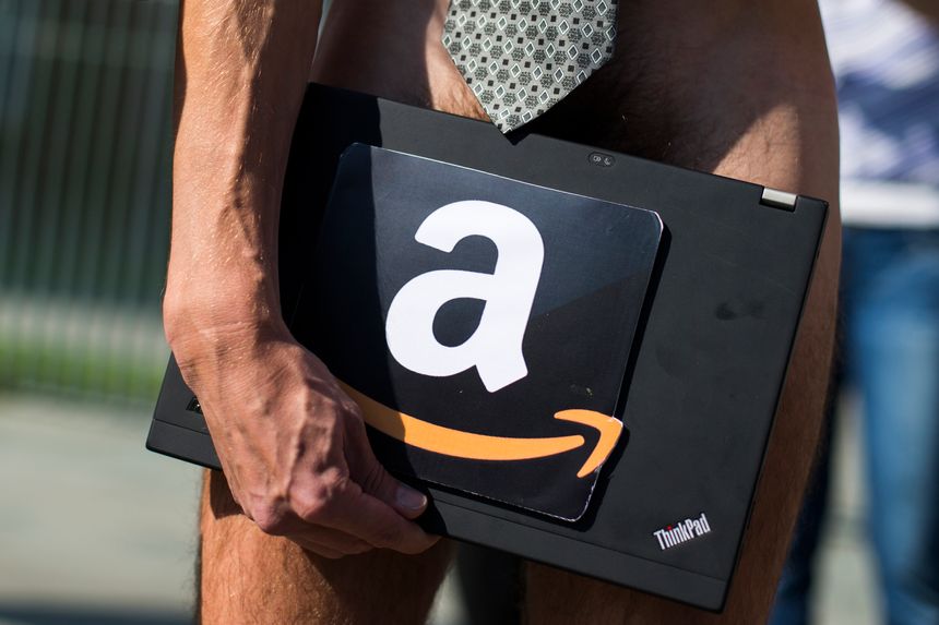 A man holds a laptop with the logo of the online retailer Amazon during a protest by the Attac pressure group outside the Chance