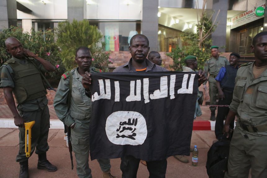 Malian security officials show a jihadist flag they said belonged to attackers in front of the Radisson hotel in Bamako