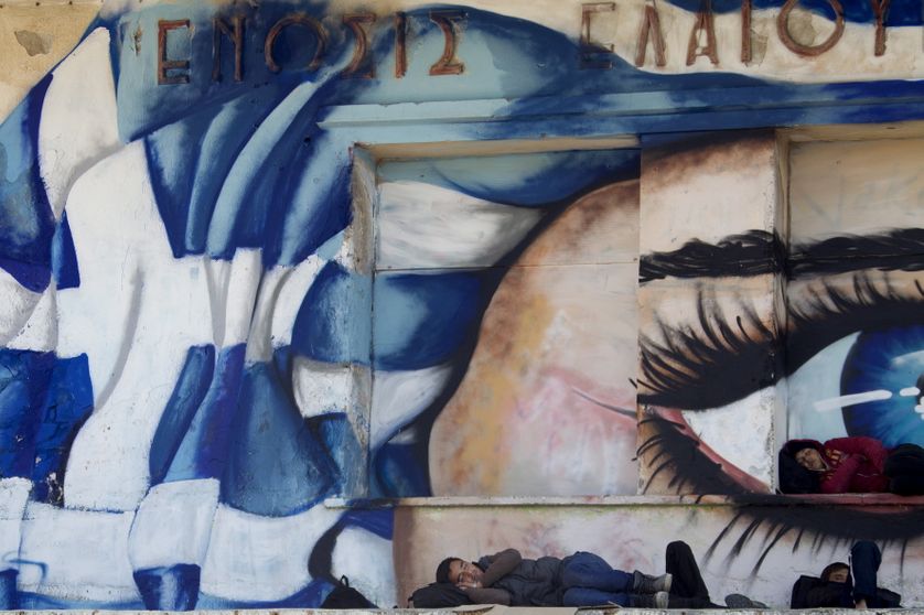 Refugees sleep in front of a graffiti covered wall on the island of Lesbos, Greece.