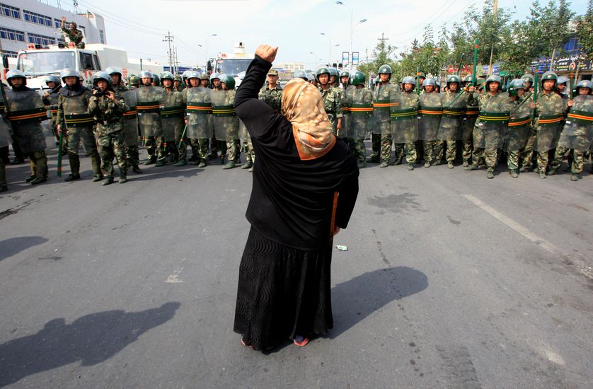 Chinese paramilitary police wearing riot gear as a crowd of angry locals confront security forces on a street in the city of Uru