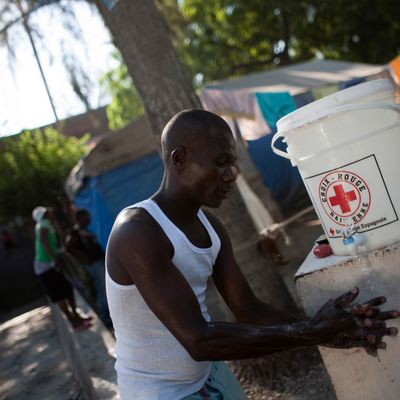 A Haïti, un homme se lave les mains grâce à une solution de la Croix Rouge