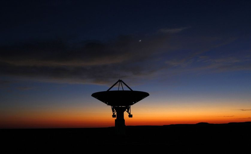 Dawn breaks over a radio telescope dish of the KAT-7 Array pointing skyward