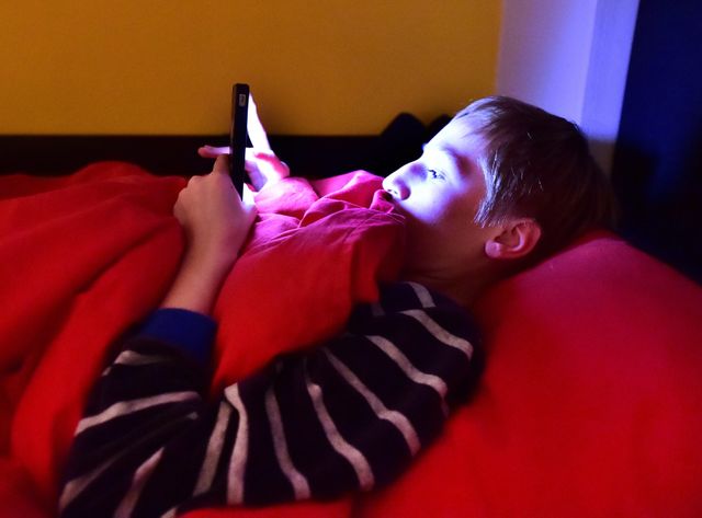 Un jeune avec son téléphone au lit