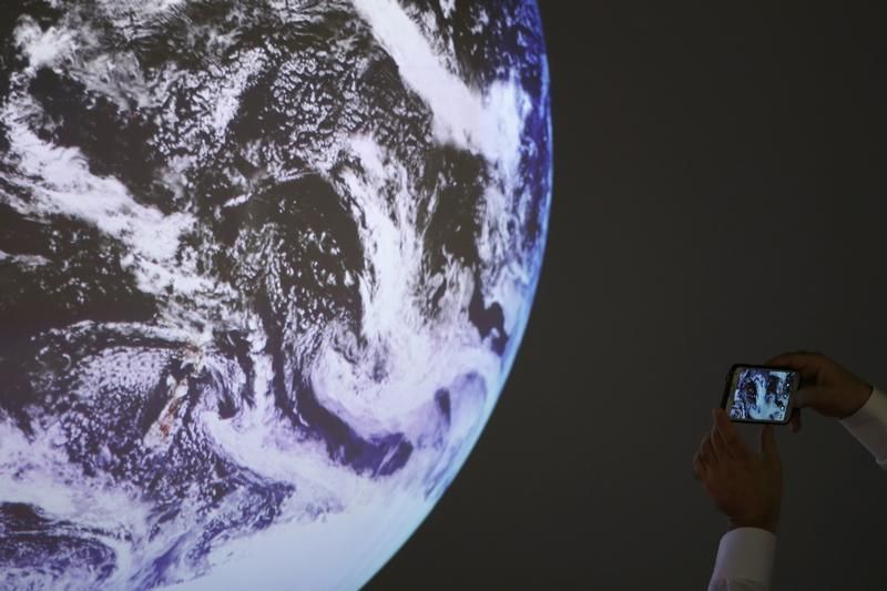 Un participant prend une photo de la réplique d'une planète durant la COP 21