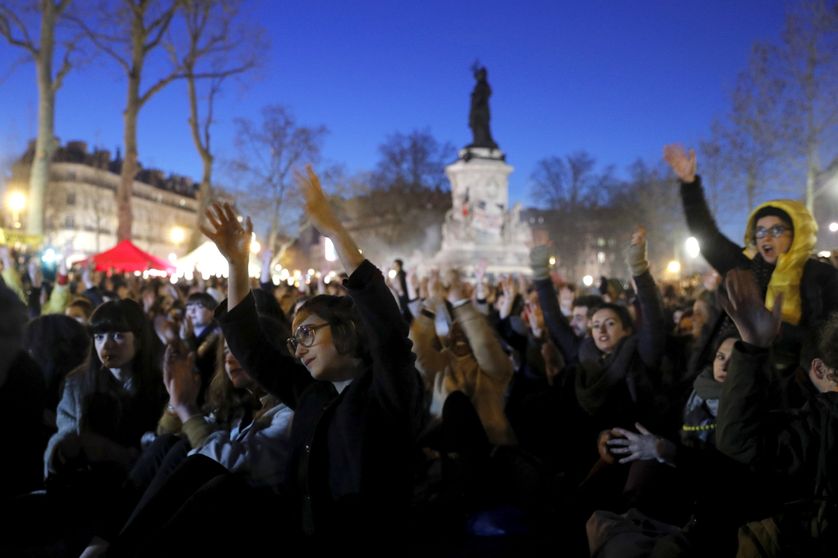 Les participant-e-s à l'AG lèvent les mains et les agitent, en aprobation