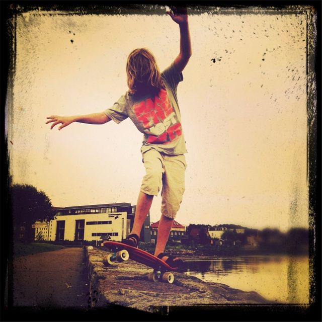 Adolescent en skate sur un muret au bord de l'eau