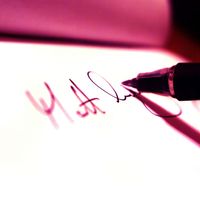 Someone writing signature with a pen and white paper
