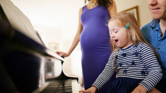 Des parents apprennent à leur fille à jouer du piano ©AFP