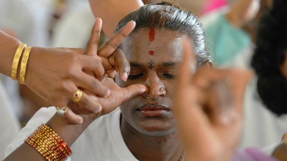 Un professeur de yoga aide un élève lors d'exercices de respiration ©AFP