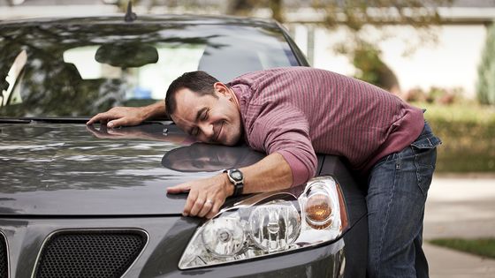 Homme faisant un câlin à sa voiture ©Getty - Meridian Studios