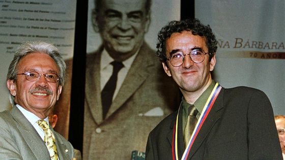 Le ministre de l'intérieur du Venezuela Ignacio Alcaya félicite Roberto Bolano après qu'il a gagné le prix Romulo Gallego le 2 août 1999. ©AFP - Bertrand Parres / AFP