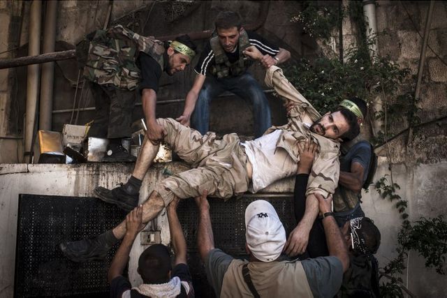 Alep, 20 août 2012. Un soldat blessé de l'Armée syrienne libre est porté à l'abri