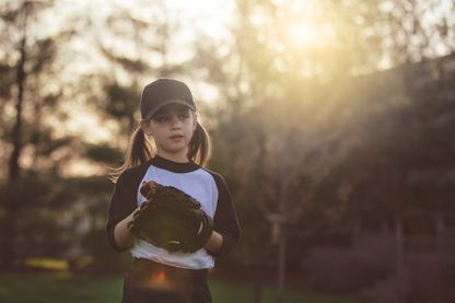 Une jeune fille s'apprête à lancer une balle de baseball Une jeune fille s'apprête à lancer une balle de baseball