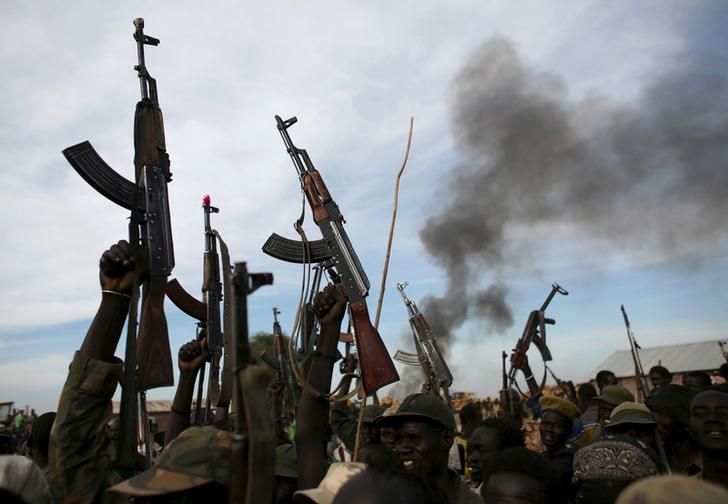 Des combattants rebelles levant fièrement leurs armes face à un feu, Sud Soudan, 13 février 2014