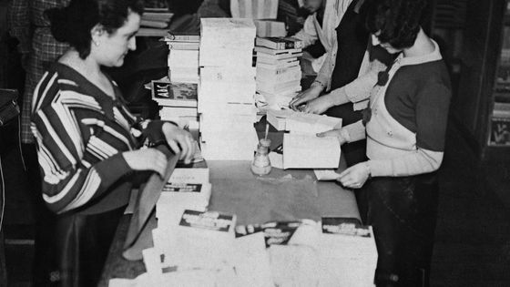 Des employés de la maison d'édition Gallimard ajustent un bandeau "Goncourt" sur le roman de Pierre Mazeline intitulé "Les loups". ©AFP - 1932