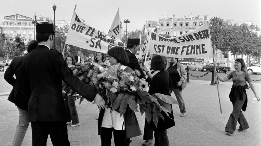 Un policier tente de refouler une dizaine de femmes venant apporter des fleurs à la "femme du soldat inconnu", le 26 août 1970 sur la place de l'Etoile à Paris