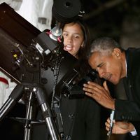 Barack Obama qui pour promouvoir la science regarde dans un téléscope