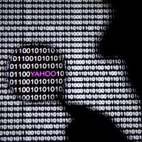 Photo illustrant un homme devant un logo Yahoo, au sein de codes informatiques, vu à travers une loupe.