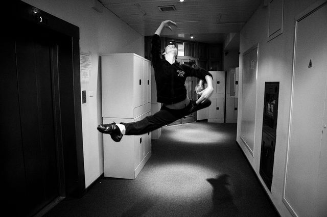 Une danseuse profite de quelques instants avant de rentrer en salle de répétition pour montrer sa technique de saut à un professeur qu’elle croise dans un couloir/ Ballet du Bolchoï 04/11