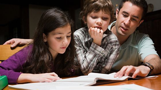 Un père aidant ses enfants à faire leurs devoirs ©AFP - CHARLES GULLUNG