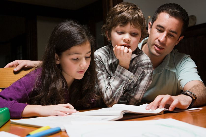 Un père aidant ses enfants à faire leurs devoirs