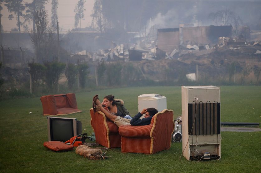Un couple se reposant dans un terrain de foot à Santa Olga après l'incendie de la forêt (Chili)