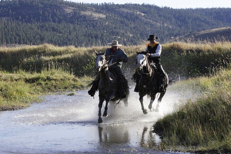 Deux cowboys chevauchant dans l'eau, aux Etats-Unis en Oregon