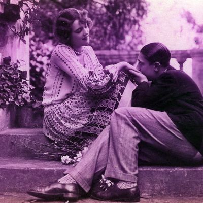 Un couple assis sur un escalier, l'homme embrasse les mains de sa compagne en la regardant, 1925