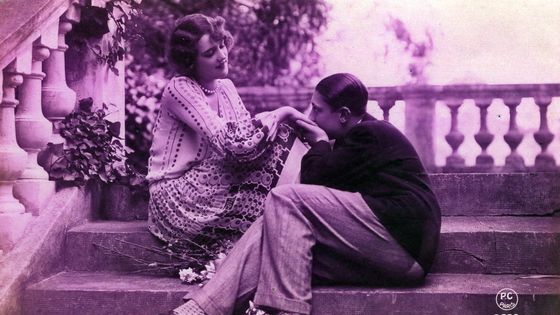 Un couple assis sur un escalier, l'homme embrasse les mains de sa compagne en la regardant, 1925 ©AFP - Leemage
