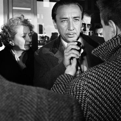 L'écrivain français Romain Gary, récompensé par le "Prix Goncourt" pour son livre "Les racines du ciel" répondant à un journaliste au côté de sa femme lors de son arrivée à l'aéroport d'Orly le 13 décembre 1956.
