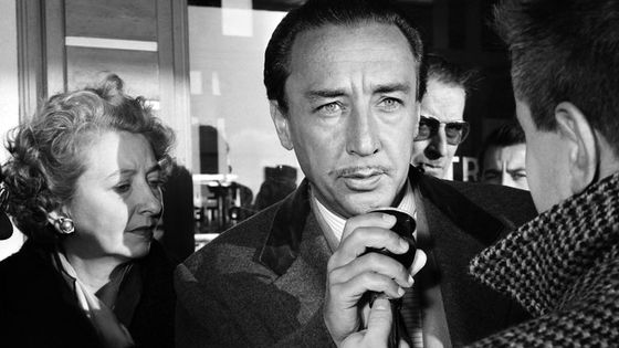L'écrivain français Romain Gary, récompensé par le "Prix Goncourt" pour son livre "Les racines du ciel" répondant à un journaliste au côté de sa femme lors de son arrivée à l'aéroport d'Orly le 13 décembre 1956. ©AFP - AFP PHOTO STRINGER