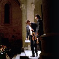 Le chef d'orchestre et violoniste, Jean-Christophe Spinosi (C), accompagné du contre-ténor David DQ Lee, salue le public le 18 septembre 2009 à l'abbaye d'Ambronay après un concert de l'ensemble