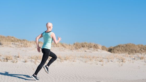 Jeune femme qui fait du jogging sur la plage après avoir subi une chimiothérapie à cause du cancer. ©Getty - Marvinh