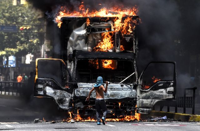 Un opposant à Maduro face à un camion en feu dans les rues de Caracas, 18 juillet 2017