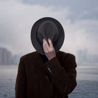 Portrait d'un homme avec le visage couvert par un chapeau.